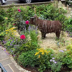 a statue of a cow in a flower garden